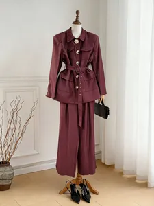 Elegant burgundy two-piece suit set with a belted jacket and wide-leg trousers for women.
