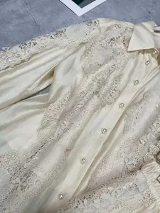 Close-up of elegant cream blouse featuring intricate water-soluble lace and pearl buttons