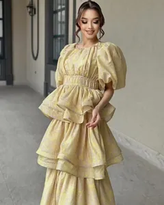 Detailed view of yellow floral tiered dress featuring puff sleeves and multi-layer ruffles