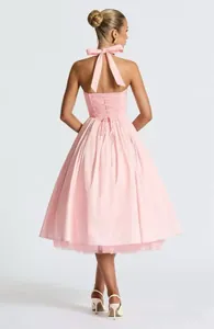Elegant back view of pink halter midi dress featuring corset lace-up detail and large bow tie