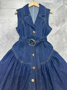 Vista dettagliata di un abito di jeans senza maniche blu scuro con bottoni dorati e cintura