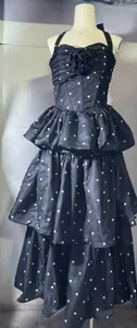 Detail van een zwarte halterjurk met polkadots en gelaagde ruches voor dames.