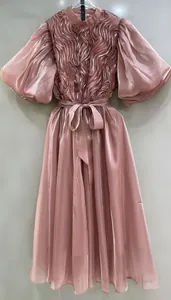 Vista de detalle de vestido rosa empolvado con mangas abullonadas y corpiño de textura.