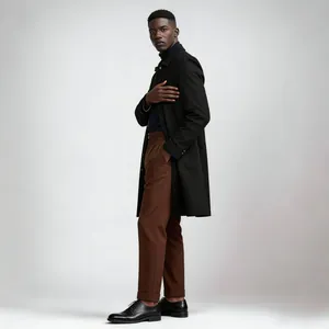Full body profile of a man wearing a black mid-length minimalist trench coat in studio.