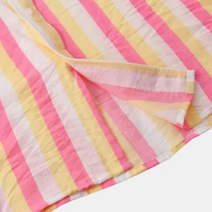 Détail d'une chemise de plage à rayures roses et jaunes montrant la texture du tissu