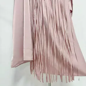 Close-up detail of smooth pink acetate fabric and long flowy fringes on a summer dress.