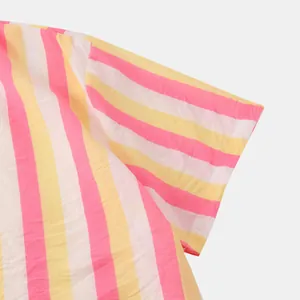 Détail en gros plan du motif rayé rose et jaune sur la manche d'une chemise de plage