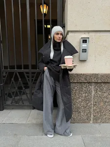 Stylish long black puffer coat worn by a model in an urban outdoor setting.