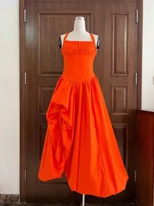 Close-up view of a vibrant orange halter-neck corset dress with an asymmetrical pleated skirt.