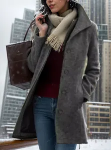 Close-up of a vintage single-breasted grey wool coat in a snowy city setting.