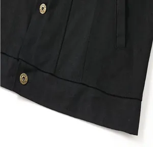 Primer plano del dobladillo de una chaqueta vaquera negra con botones metálicos.