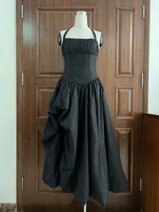 Elegant black halter maxi dress with corset waist and pleated irregular skirt on mannequin.