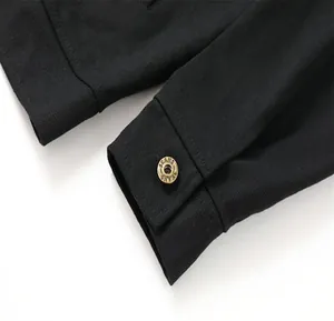 Primer plano detallado del puño de una chaqueta vaquera negra con botón de latón antiguo