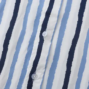 Gros plan du tissu à rayures ondulées bleu et blanc avec boutons d'une chemise de plage