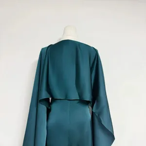 Back view detail of a teal satin dress with a matching long-sleeved cropped capelet