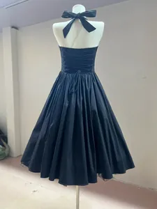 Detailed back view of a black halter-neck midi dress with elegant lace-up ribbon design.