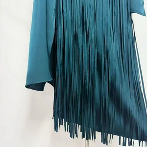 Close-up detail of dark teal acetate dress featuring long vertical tassel fringe texture
