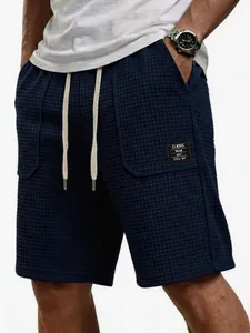 Detailansicht der dunkelblauen Waffelstrick-Shorts mit Taschenlabel und Stofftextur