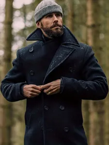 Detail view of a men's British style navy wool pea coat in a rustic winter forest setting