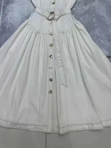 Dettaglio dell'abito in denim bianco senza maniche con bottoni e cintura
