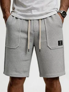 Detailansicht graue Waffelstrick-Herrenshorts mit aufgesetzter Tasche und Kordelzug am Bund