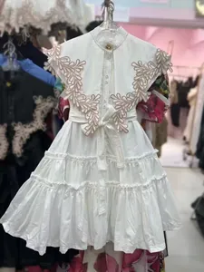 Detailed view of a white embroidered ruffle dress featuring tiered skirt and floral patterns
