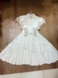 Elegant white resort style embroidered A-line dress with ruffles and a tie waist belt