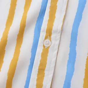 Gros plan sur le tissu d'une chemise à rayures bleues et jaunes avec bouton blanc