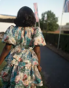 Back view of a multi-layer floral tiered dress with bubble sleeves in outdoor sunlight