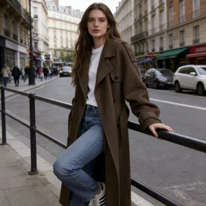 Detail view of an elegant long brown wool coat styled with jeans on a European street background