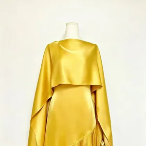 Close-up of yellow satin dress featuring an asymmetrical pleated hem and matching shawl.
