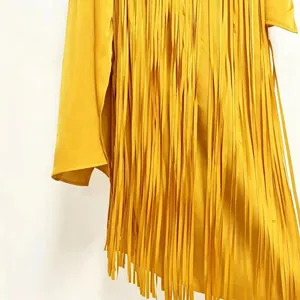 Close-up detail of a bright yellow dress with long flowing fringe tassels and silky texture
