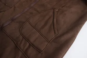 Dettaglio macro di una giacca in velluto marrone scuro con cuciture tasca e zip testurizzata.
