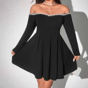 Close-up detail of a black off-the-shoulder dress featuring elegant pearl trim on the neckline
