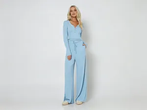 Gesamtansicht des hellblauen Rippstrick-Lounge-Sets mit geknöpftem Oberteil und weiter Hose.