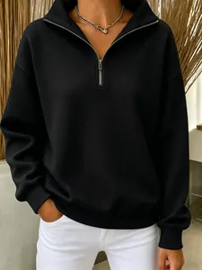 Détail d'un sweat-shirt noir en maille gaufre avec demi-zip et coupe décontractée ample.