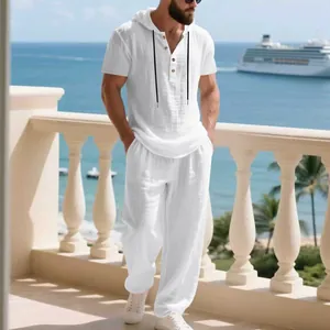 Uomo che indossa un completo casual in lino bianco con felpa e pantaloni larghi in spiaggia