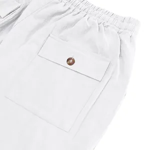Close-up of white linen trousers with elastic waist and buttoned flap pocket.