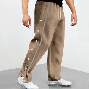 Détail de pantalon marron pour homme avec boutons-pression latéraux et bandes décoratives.
