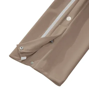 Gros plan détaillé du pantalon kaki avec rayures latérales et boutons-pression en métal.
