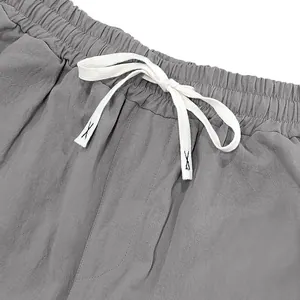 Close-up detail of elastic waistband with white drawstring on men's grey linen trousers