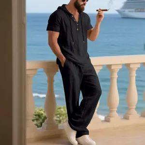 Vista completa del set in lino nero con cappuccio da uomo indossato dal modello sul balcone