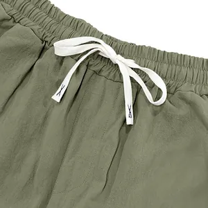 Close-up detail of the elastic waistband and white drawstring on olive green linen pants