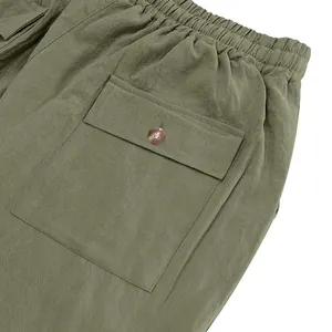 Close-up detail of green linen cargo pants showing elastic waistband and button pocket