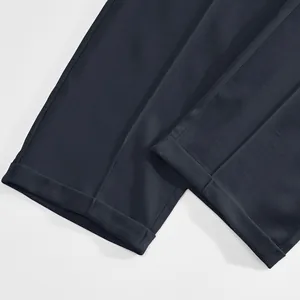 Vue détaillée montrant la couture précise de l'ourlet sur un pantalon de costume bleu marine.