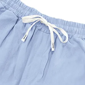 Close-up of elastic waistband and white drawstring on light blue linen beach pants.