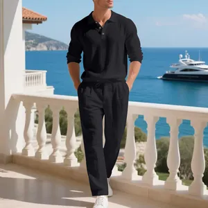 Man wearing a black linen casual set on a luxury balcony overlooking the sea.