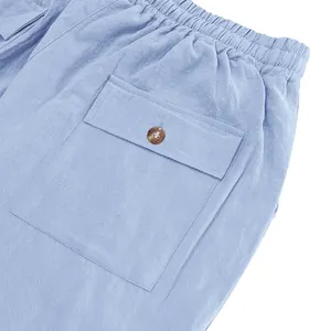 Detail view of men's light blue linen trousers with cargo pocket and elastic waist.