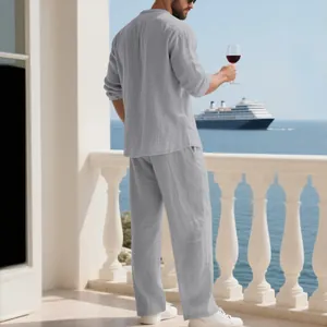 Vista posteriore di un uomo in completo di lino grigio con vino su un balcone di lusso.