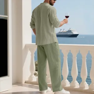 Uomo in completo di lino verde salvia su un balcone con vista oceano e nave